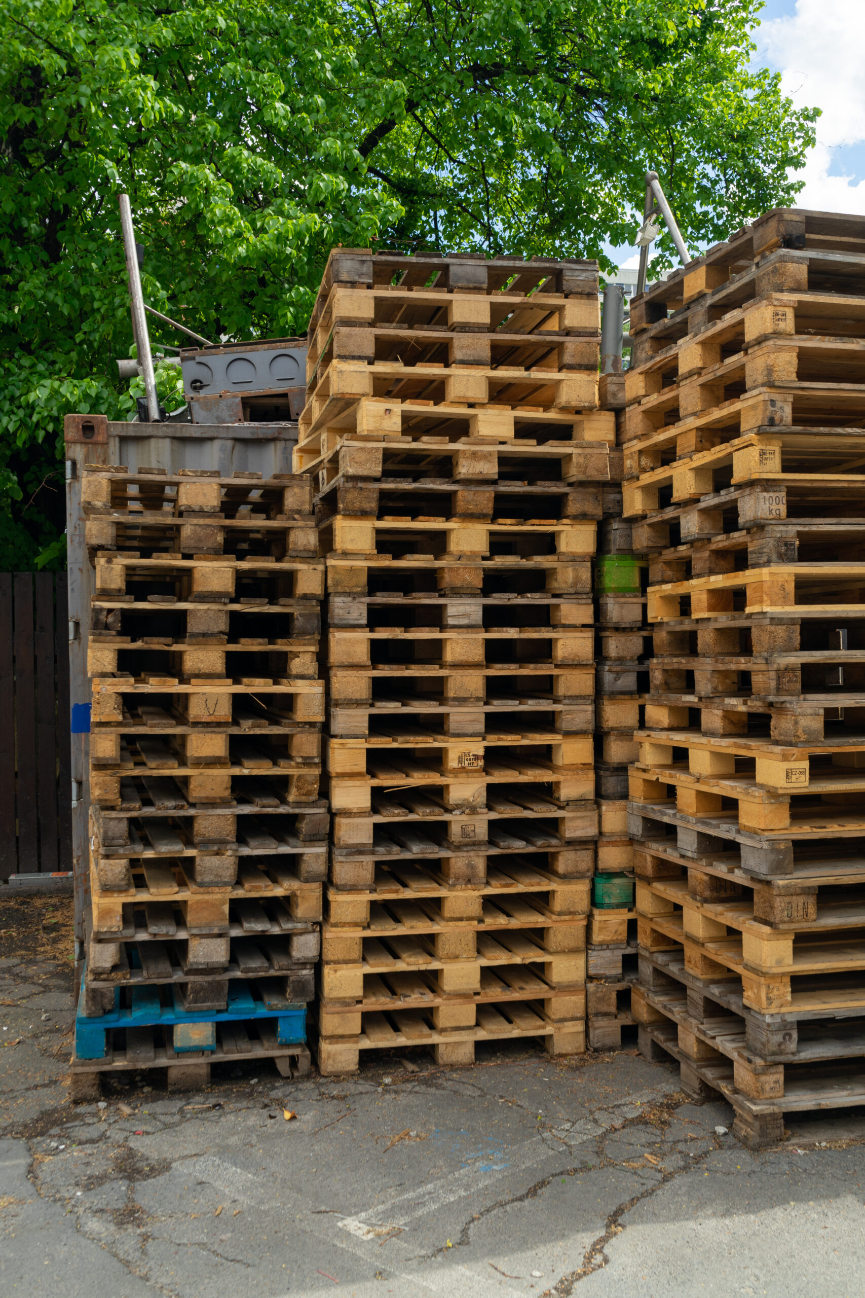 Primer plano vertical de palés de madera vacíos apilados unos encima de otros al aire libre.